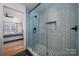 Close-up of the bathroom shower with blue and grey tile and glass enclosure, and view into the bedroom at 230 Pond View Ln, Fort Mill, SC 29715