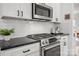 Kitchen features stainless steel appliances, white cabinets, dark countertops, and tile backsplash at 230 Pond View Ln, Fort Mill, SC 29715