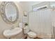 Cozy half bath with a pedestal sink, decorative mirror, toilet, and framed art above the toilet at 6008 Nuthatch Ct, Charlotte, NC 28277