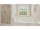 Bright bathroom features a soaking tub, shower with glass doors, and tile floors at 6008 Nuthatch Ct, Charlotte, NC 28277