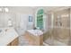 Bright bathroom featuring a soaking tub, glass shower, and large arched window overlooking lush greenery at 727 Mayfield Ct, Fort Mill, SC 29715