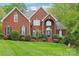 Beautiful red brick home with a manicured lawn, mature landscaping and a charming, symmetrical facade at 727 Mayfield Ct, Fort Mill, SC 29715