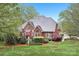 Two-story red brick home boasts a mature landscaped yard with a lush lawn and colorful plantings at 727 Mayfield Ct, Fort Mill, SC 29715