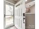 View of the entryway showcasing a white front door with glass panel, neutral walls, and glimpses of the kitchen at 810 Rock Lake Gln, Fort Mill, SC 29715