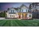 Charming two-story home with a manicured lawn and inviting front porch with bright red chairs at 1005 Palace Ct # 58, Indian Trail, NC 28079