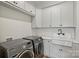 Convenient laundry room with gray washer and dryer, large sink and ample white storage cabinets at 101 S Shore Dr, Belmont, NC 28012