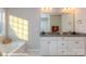 Bright bathroom featuring dual vanity sinks, a soaking tub, and a large window at 116 Asmodean Ln, Troutman, NC 28166
