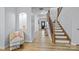 Bright hallway featuring hardwood floors, staircase, and a decorative alcove with a chair at 1205 Brooksland Pl, Waxhaw, NC 28173
