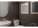 Stylish powder room featuring a modern round mirror, white toilet, and unique wall art at 13943 Penbury Ln # 376, Charlotte, NC 28278