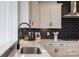 Close-up of modern kitchen featuring white cabinets, quartz countertops and a black subway tile backsplash at 13943 Penbury Ln # 376, Charlotte, NC 28278
