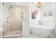 Bright bathroom featuring a soaking tub, tiled walk-in shower with glass door, a pendant light, and plantation shutters at 15124 Hugh Mcauley Rd, Huntersville, NC 28078