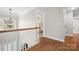 Well-lit hallway featuring hardwood floors, white railings, and an elegant light fixture at 15124 Hugh Mcauley Rd, Huntersville, NC 28078