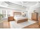 Bright main bedroom featuring tray ceilings, hardwood floors, a ceiling fan, and matching bedside tables and dressers at 15124 Hugh Mcauley Rd, Huntersville, NC 28078
