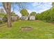 Well-maintained backyard with level lawn, mature tree, and a stone fire pit, ideal for outdoor gatherings at 1644 Morningside Dr, Charlotte, NC 28205