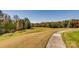Scenic view of the golf course with lush green grass, trees and a concrete cart path under a bright blue sky at 16744 Ashton Oaks Dr, Charlotte, NC 28278