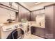 Well-equipped laundry room with modern washer and dryer, custom cabinetry, and a utility sink at 16744 Ashton Oaks Dr, Charlotte, NC 28278