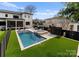 Inviting backyard pool and spa feature travertine tile and manicured synthetic turf, and a black privacy fence at 300 Mammoth Oaks Dr, Charlotte, NC 28270