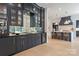 Elegant kitchen with a mirrored backsplash, dark cabinets, wine cooler and adjacent seating area, bathed in natural light at 401 Woodland St, Davidson, NC 28036