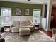 A living room featuring a cream sofa, area rug, two windows, two side tables, hardwood floors, and painted walls at 4130 Brownwood Nw Ln, Concord, NC 28027