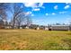 View of grassy backyard featuring metal building, shed, and neighboring houses on a sunny day at 655 Mock Mill Rd, Statesville, NC 28677