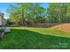 Beautiful backyard with mature trees, a lush green lawn, and a charming playset in the distance at 1119 Lytton Ln, Matthews, NC 28104