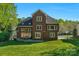 Rear view showcasing a brick home with a spacious backyard and inviting outdoor living space at 1119 Lytton Ln, Matthews, NC 28104