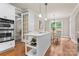Kitchen island with sink, white cabinets, stainless steel appliances, pendant lights, hardwood floors at 1119 Lytton Ln, Matthews, NC 28104