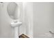 Bathroom featuring white pedestal sink, oval mirror, and gray wood flooring at 126 Orville Rd, Statesville, NC 28677