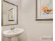 Modern powder room features pedestal sink, framed mirror, and elegant artwork at 13011 Hampton Bay Ln, Charlotte, NC 28262