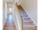 Bright stairway features carpeted steps, white risers and wood railing, leading to a hallway with hardwood floors at 1829 Augustine St, Monroe, NC 28112