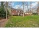 Green backyard with a mature trees surrounds the brick house at 1916 Dugan Dr, Charlotte, NC 28270