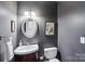 A stylish half bath featuring a corner sink, decorative mirror, and painted dark gray walls at 1916 Dugan Dr, Charlotte, NC 28270