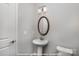 Stylish powder room featuring a pedestal sink, oval mirror, modern light fixture, and a neutral color scheme at 19732-B School St, Cornelius, NC 28031