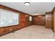 Living room featuring wood paneling, carpet, and large window providing ample natural light at 213 Turner Rd, Gastonia, NC 28056