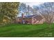 Back exterior view of brick home with mature trees, a lush lawn, and a chimney at 2750 Morgan Rd, Gold Hill, NC 28071