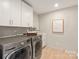 Bright laundry room features stainless steel washer and dryer, white cabinets, and light hardwood flooring at 2924 Springs Dr, Charlotte, NC 28226