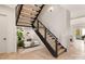 Modern staircase with wooden steps, black railings, and a cozy seating area with plants underneath at 2924 Springs Dr, Charlotte, NC 28226