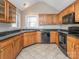 Well-lit kitchen with stainless steel appliances, dark countertops, tile flooring, and wood cabinetry at 3274 Roberta Farms Sw Ct, Concord, NC 28027