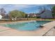 A community pool surrounded by a black metal fence, mature trees, and residential buildings at 3274 Roberta Farms Sw Ct, Concord, NC 28027