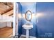 Powder room with pedestal sink, decorative mirror, blue walls, and view into the kitchen at 4846 Midway Sand Rd, Hickory, NC 28601