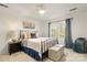 Bedroom with an iron frame bed, side table and lamp with window view with blue curtains at 5217 Camilla Dr, Charlotte, NC 28226