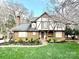 Charming Tudor-style home featuring a brick facade, dark trim, manicured lawn, and beautiful landscaping at 5217 Camilla Dr, Charlotte, NC 28226