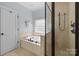 Bathroom with a built-in tub, shower, and neutral tiles, complemented by a window providing natural light at 643 Mcalway Rd, Charlotte, NC 28211