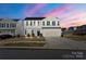 Two-story home with blue shutters, a two-car garage, and a well-manicured front lawn at sunset at 8010 Bruce St, Charlotte, NC 28215