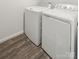 A new, white front load washer and dryer sit on top of wood-look flooring in this laundry area at 8010 Bruce St, Charlotte, NC 28215