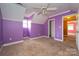 A bedroom with purple walls and dirty carpet features a window and entry door, requiring renovation at 82 Paddington Sw Dr, Concord, NC 28025