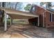 A carport attached to a brick house shows signs of neglect and disrepair, requires clean up and renovation at 82 Paddington Sw Dr, Concord, NC 28025