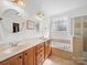 Bright bathroom with double vanity, soaking tub, tiled floor, and natural light from a window at 108 Avaclaire Way, Indian Trail, NC 28079