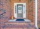 Close-up of the front door with a wreath, flanked by brickwork and a small potted plant at 108 Avaclaire Way, Indian Trail, NC 28079