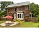Charming brick home with a well maintained backyard, red umbrella, and newly planted tree at 1120 Millwright Ln, Matthews, NC 28104